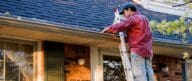 Man on ladder inspecting or cleaning gutters on a house.