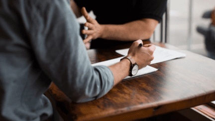 Men discussing home inspection report at table.