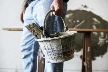 Home foundation repair professional holding bucket of tools.