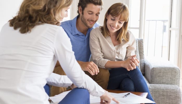 Couple reviewing proceeds of selling house with small kids in meeting with agent.