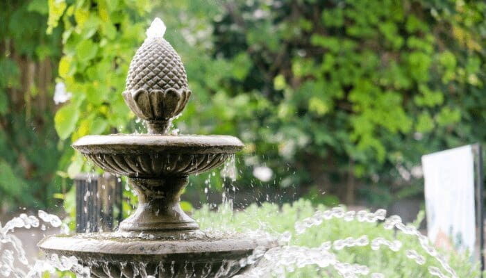 A fountain outside a house with road noise.