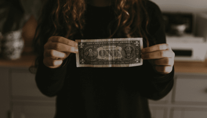 A person holding a dollar to pay for a home.