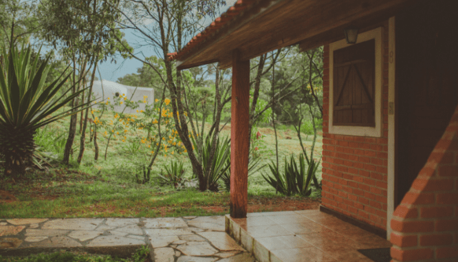 A porch for a bungalow house with tropical plant landscaping.