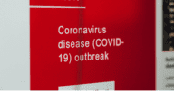 A red sign that reads "Coronavirus diease (COVID-19) outbreak."