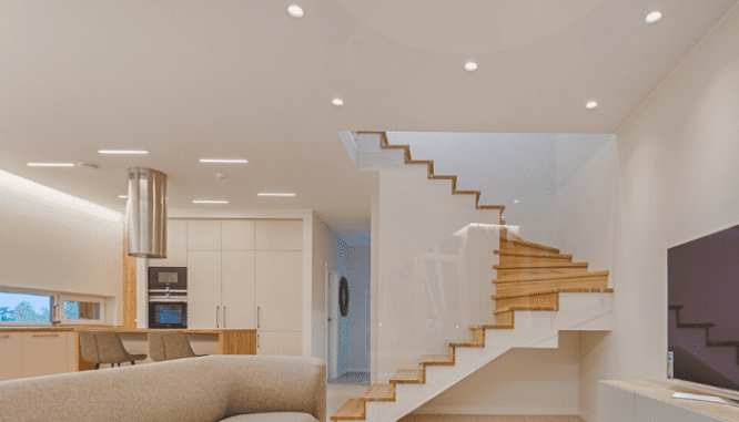 A living room and kitchen that has recessed lighting, a home improvement idea for a small house.