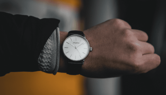 A hand wearing a watch and checking the time.