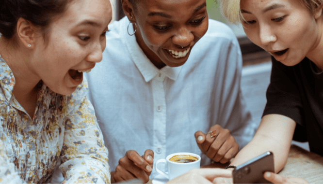 A group of women who are bidding on a house at auction using a cell phone.