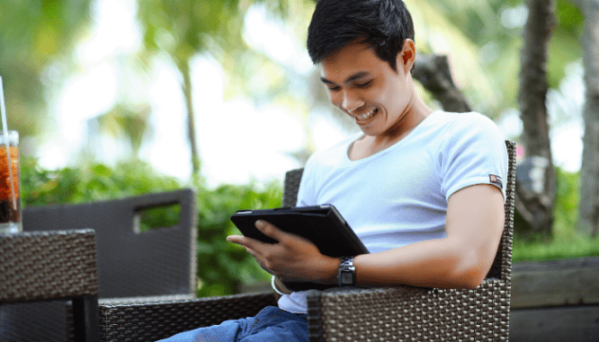 A man smiling down at a tablet because he has multiple offers.