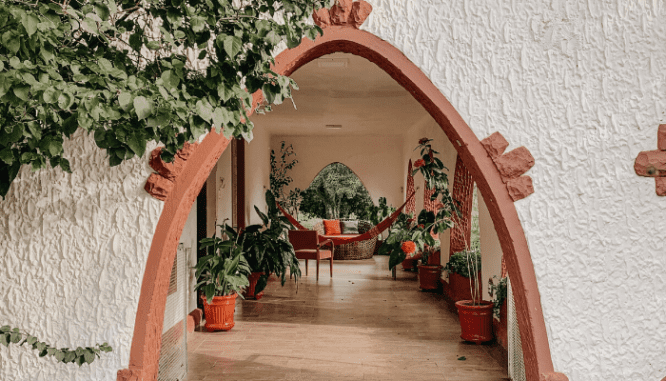 An adobe and white porch with a hammock and lots of potted plants, which can add value to a home.