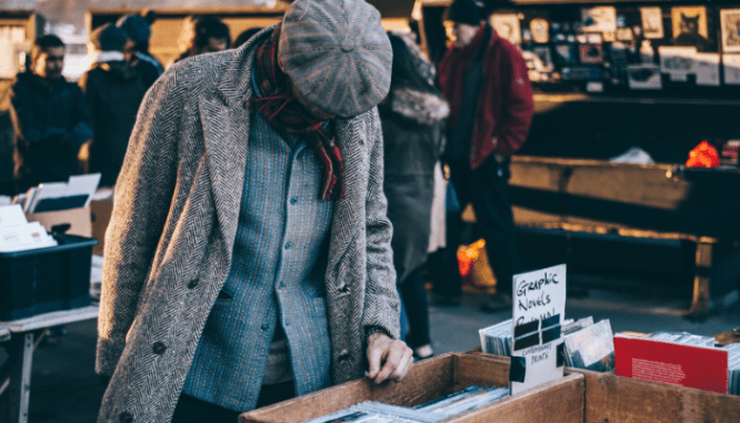 Someone in a winter coat and hat looking through some records for sale at a garage sale.