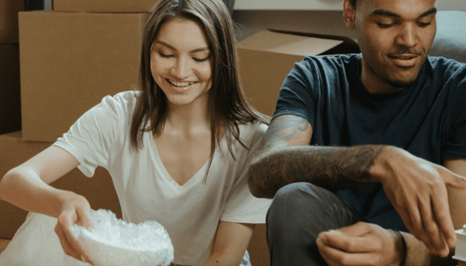 A couple preparing things and packing things into boxes for moving into a new house.