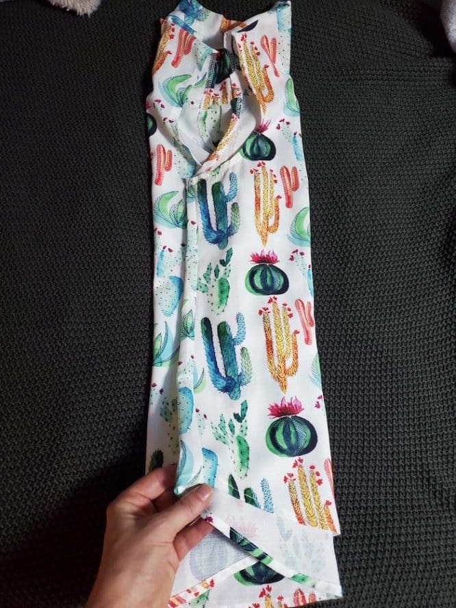 A shirt with a cactus print getting folded into thirds from sleeve to sleeve for a flat-fold step to show how to pack clothes for moving