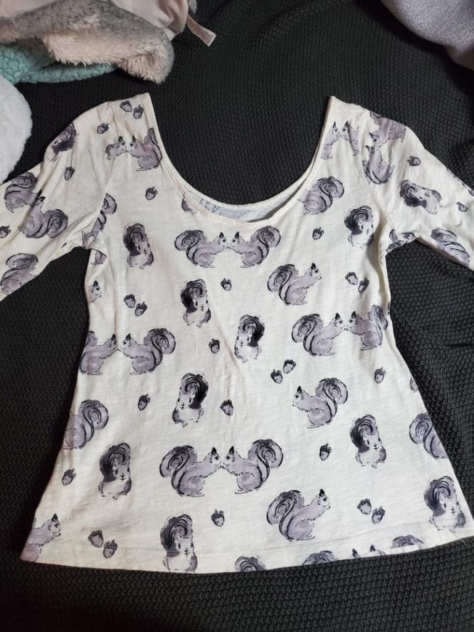 A shirt with a squirrel print laid flat in preparation to be folded in the Kon-Mari method to show how to pack clothes for moving day