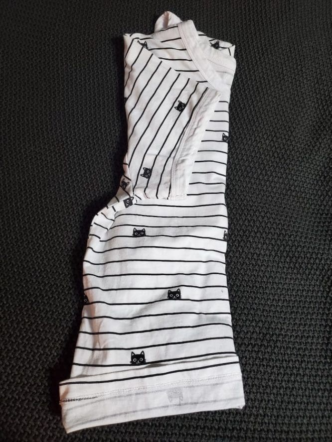 A shirt with a lined cat print with its last sleeve folded in for a military roll to show how to pack clothes for moving
