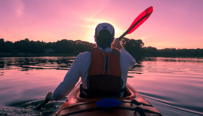A person kayaking to a waterfront home.