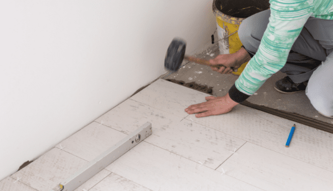A person installing laminate flooring to increase home value.