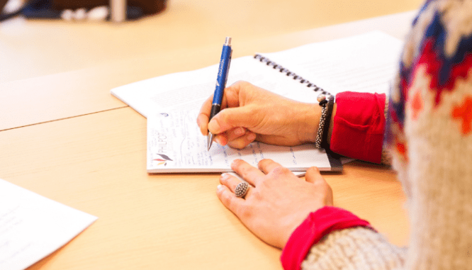 A woman writing notes about a leaky basement.