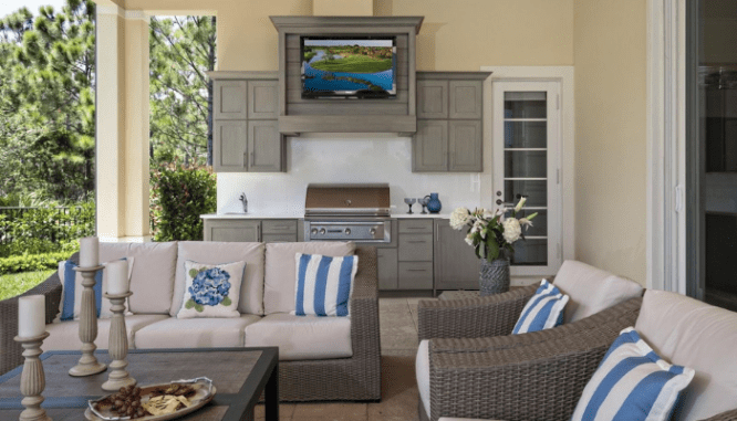 A beige outdoor kitchen with a TV.