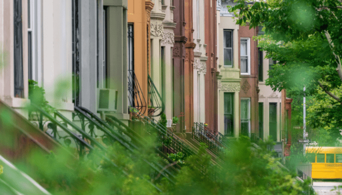 An image of a street of brownstones with trees to demonstrate what a brownstone is.