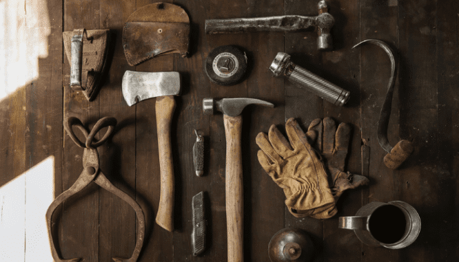 A handyman's tools are on a wooden table in a rental property.
