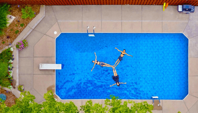 People swimming in a pool with a rectangular design.