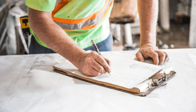 An image of a construction worker installing a sump pump under a house.