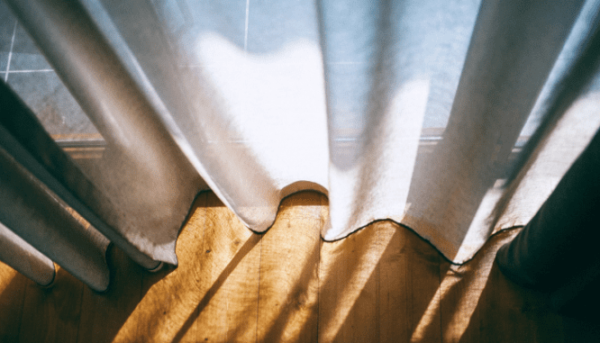 A curtain letting in natural light in a home that was sustainably designed.