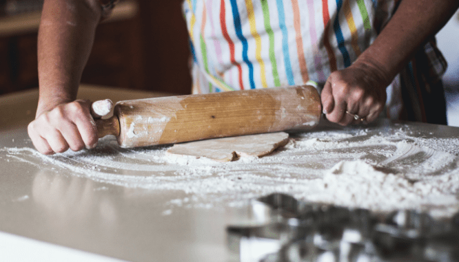 A woman rolling dough that will cook in the home appliance.