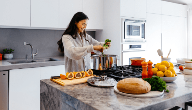 A woman cooking in a kitchen full of appliances purchased during Memorial Day sales.