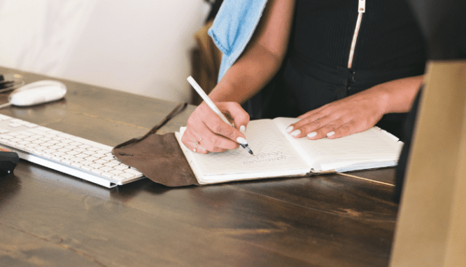 An image of a woman writing to demonstrate the process of how to make an offer on a house with a realtor.