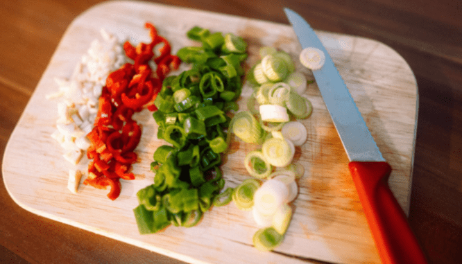 An image of a cutting board with vegetables to demonstrate a list of household items needed for a new home.