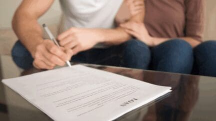 An image of two people signing a loan to demonstrate the cost to refinance.