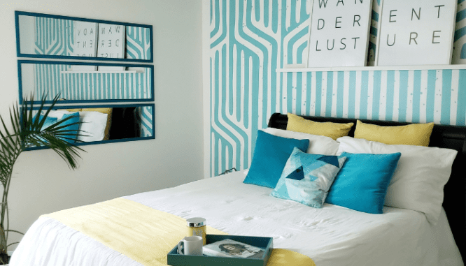 Three rectangular mirrors are hung in a stacked arrangement in a bedroom, which is one way to decorate with mirrors.