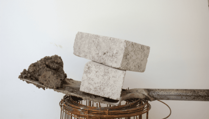 A shovel holding bricks that will be formed into a wall for decorative landscaping.