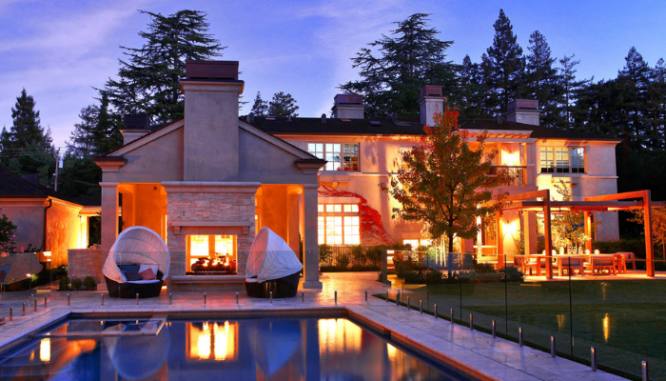 An outdoor room with a fireplace and a pool.