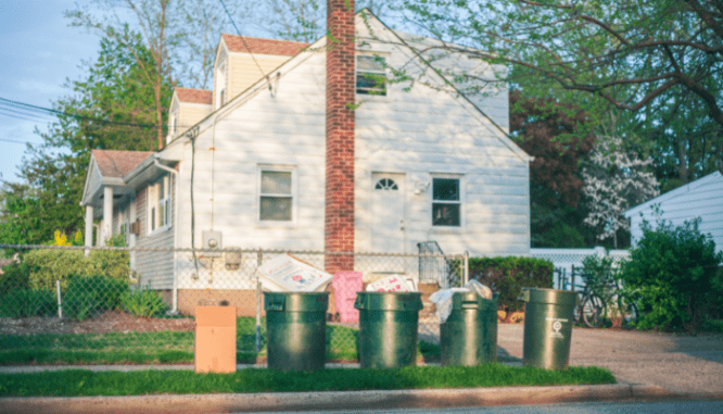 A house in a homeowners association with garbage cans in front of it.