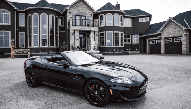 A car driving by a house to do an appraisal for a home.