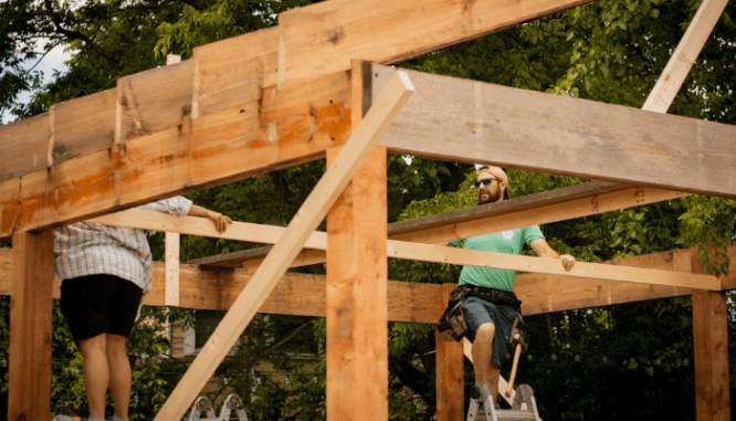 Two people building an outdoor pavilion for shade as an exterior home improvement.