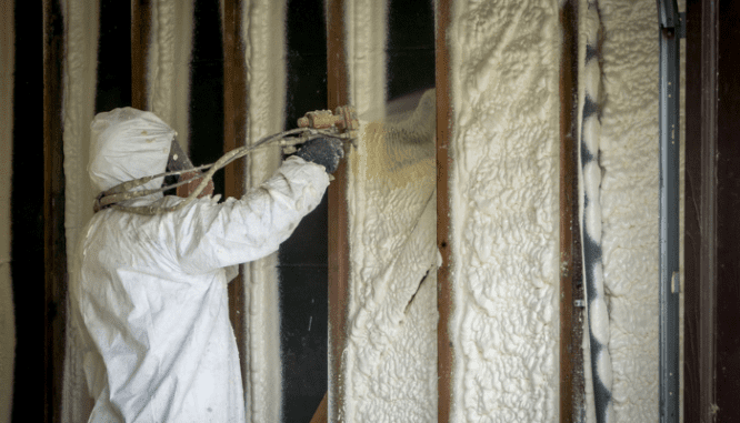 A person insulating an attic with spray foam.