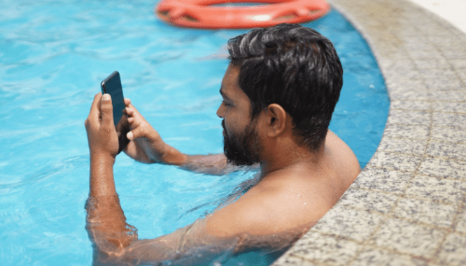 A person on their phone in their swimming pool, which could increase a home's value.