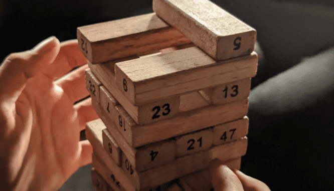 A Realtor playing with Jenga pieces with numbers on them.