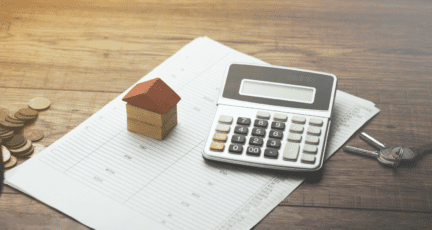 A calculator and small wooden house to indicate pricing to sell.