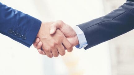 Two people shaking hands about real estate.