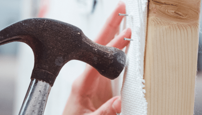 A person hammering nails on a house they might have bought through a first time home buyer loan.