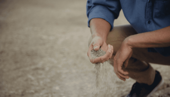 A person looking at soil on their property as part of the home inspection.
