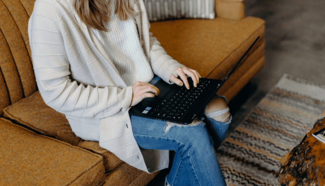 A woman using a laptop to search if you need a lawyer to buy a house.