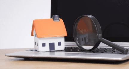 A house and magnifying glass on a laptop, to indicate researching if homelight is legitimate.