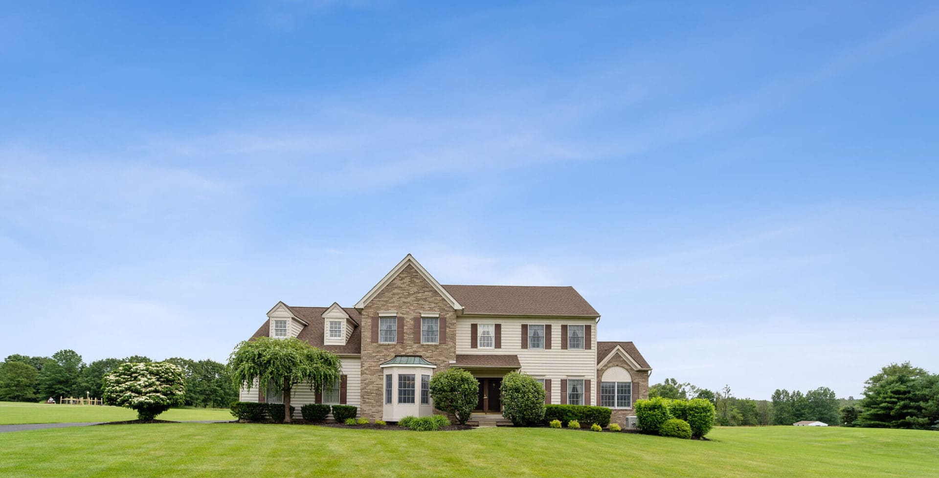 Large home with green lawn, representing insights from top agents on housing trends, pricing, and market activity (2019–2025)