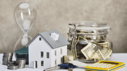 Image depicting key elements for understanding house buying tips, including a house model on a white table, an hourglass, calculator, money, and keys