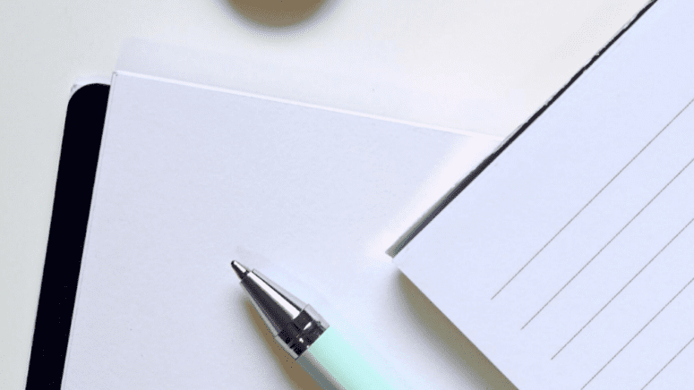 A pen and paper to write questions to ask a real estate agent.